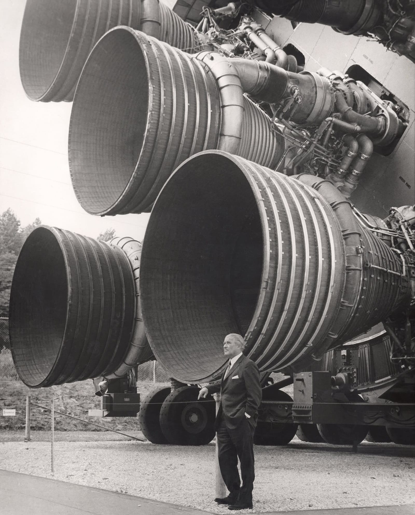 Wernher von Braun standing in front of Saturn V S-IC first-stage engines.